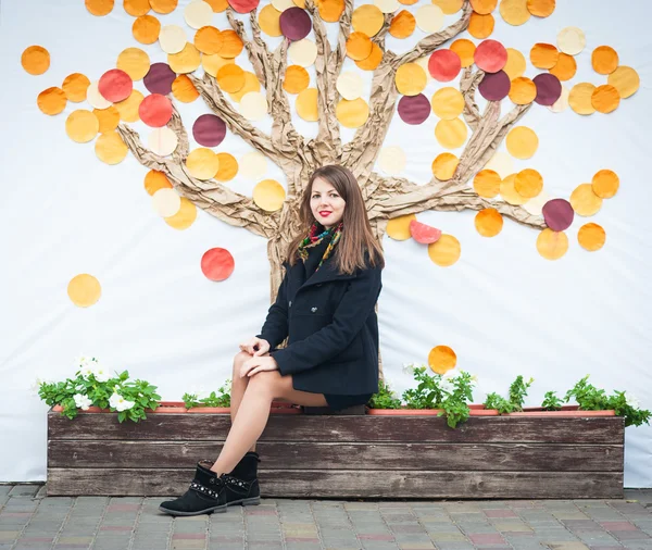 Mujer sentada en el banco, fondo del árbol de otoño —  Fotos de Stock