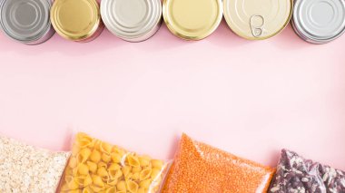Pembe arka planda karantina süresi için gıda stoku krizi çerçevesi. Yulaf ezmesi, makarna, mercimek, konserve yiyecek. Yiyecek teslimatı, bağış, koronavirüs karantinası.