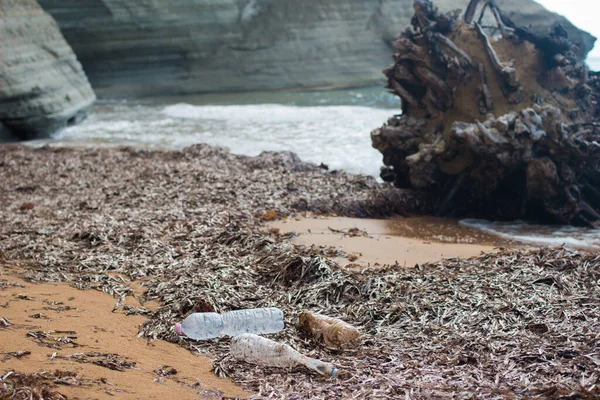 Environmental pollution, ecological problem concept. Used dirty plastic water bottles washed up on shore of tropical beach.Trash on sand beach highlighting global worldwide crisis of plastic