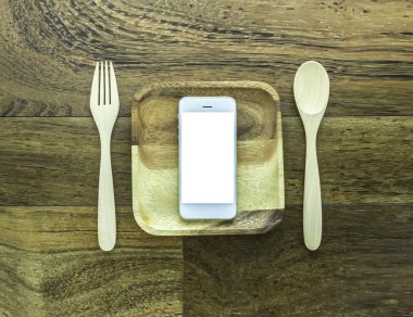 Tahta tabağı, kaşığı, çatalı olan akıllı telefon.