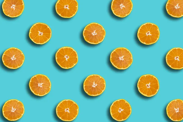 Colorful fruit pattern of Sumo mandarin fresh orange slices on blue background, spring, summer cocept.