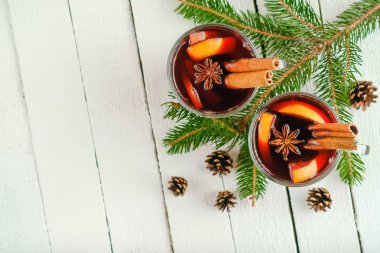 Elma, portakal, tarçın ve yıldız anasonlu cam bardaklarda sıcak şarap. Karanlık bir arka planda, köknar dalı fotokopi alanı olan sıcak Noel içeceği..