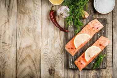 Otlu taze somon bifteği, limon, biberiye ve baharatlar kırsal bir arka plan fotokopi alanında kesim tahtasında..