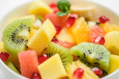 Ev yapımı taze meyve salatası ile kase: mango, greyfurt, nar, kivi, hafif arkaplanda muz..
