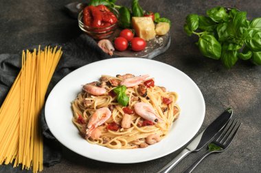 Deniz mahsullü makarna, güneşte kurutulmuş domates, parmesan ve fesleğen, arka planda açık bir tabakta, fotokopi alanı..