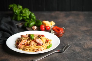 Deniz mahsullü makarna, güneşte kurutulmuş domates, parmesan ve fesleğen, arka planda açık bir tabakta, fotokopi alanı..