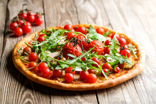 Traditional italian pizza with cherry tomatoes on a wooden shovel on a dark background.