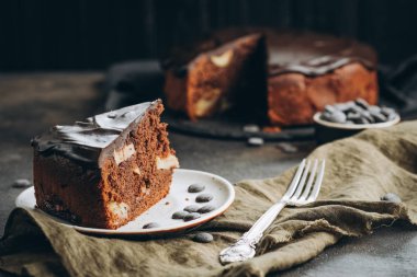 Geleneksel İtalyan çikolatalı keki koyu arkaplanda elmalar ve tarçınlı.