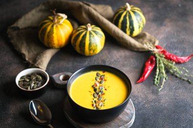 Kabak tohumlu ev yapımı balkabağı çorbası karanlık bir zeminde kabak kabağı, baharat ve otlarla fotokopi alanı..