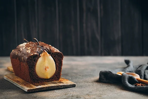 Homemade pastries. Chocolate cake with pear and cinnamon on a dark background copy space