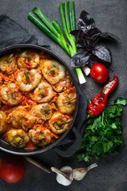 Pilav, et ve baharatla doldurulmuş biberler koyu bir arka plan manzarasında, karanlık bir tavada.