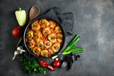 Pilav, et ve baharatla doldurulmuş biberler koyu bir arka plan manzarasında, karanlık bir tavada.