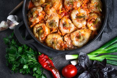 Pilav, et ve baharatla doldurulmuş biberler koyu bir arka plan manzarasında, karanlık bir tavada.