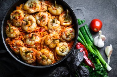 Pilav, et ve baharatla doldurulmuş biberler koyu bir arka plan manzarasında, karanlık bir tavada.