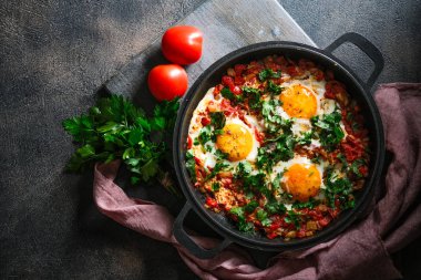 Demir bir tavada yumurta, domates ve maydanozlu Shakshuka. Üst görünüm kopyalama alanı