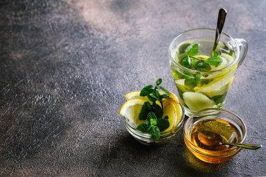 Limon dilimli taze zencefil çayı, koyu arkaplanda nane ve bal..
