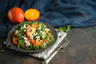 Sağlıklı salata, hurma, roka, beyaz peynir ve kabak tohumları koyu bir arka planda. Vejetaryen menüsü, sağlıklı yiyecekler. Vitamin eksikliğinin önlenmesi. Üst görünüm.