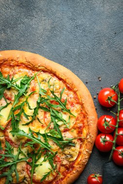 Geleneksel İtalyan pizzası jambon, mozzarella, fesleğen, roka ve domatesli koyu arka planda fotokopi alanı.