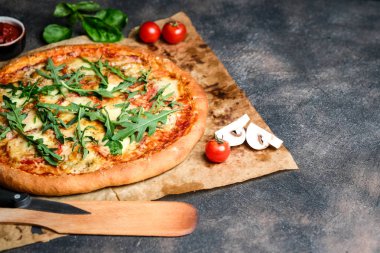 Geleneksel İtalyan pizzası jambon, roka, mozzarella, fesleğen ve domatesli koyu arka planda fotokopi alanı..