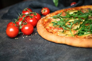 Geleneksel İtalyan pizzası jambon, roka, mozzarella, fesleğen ve domatesli koyu arka planda fotokopi alanı..