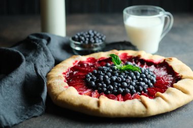 Ev yapımı destek. Erikli lezzetli galet ve koyu arkaplanda bir bardak sütle yabanmersini..