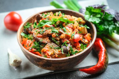 Sebze sote ya da caponata, ya da patlıcan, biber, domates ve otlarla dolu siyah arka planda kırsal bir kase.. 