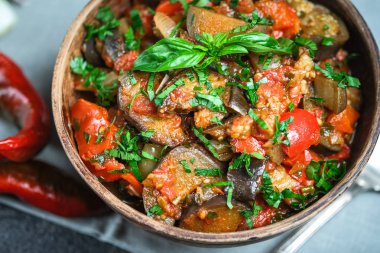 Sebze sote ya da caponata, ya da patlıcan, biber, domates ve otlarla dolu siyah arka planda kırsal bir kase.. 