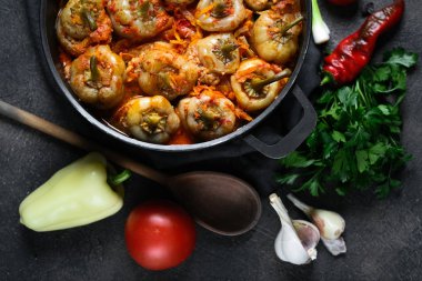 Pilav, et ve baharatla doldurulmuş biberler koyu bir arka plan manzarasında, karanlık bir tavada..