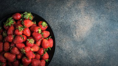 Siyah tabakta taze çilek. Karanlık bir arka planda. Üst Manzara. Boşluğu kopyala.