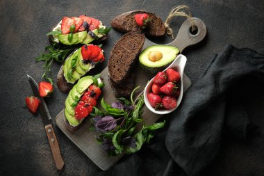Avokado, peynir, çilek, otlar ve tohumlu bir tost veya sandviç. Bir bruschetta ya da sağlıklı bir aperatif fikri. Sağlıklı vejetaryen kahvaltısı..