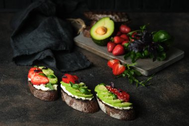 Avokado, peynir, çilek, otlar ve tohumlu bir tost veya sandviç. Bir bruschetta ya da sağlıklı bir aperatif fikri. Sağlıklı vejetaryen kahvaltısı.