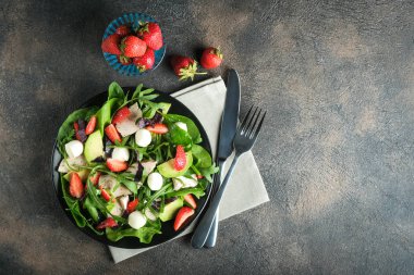 Taze çilekli salata, roka, fesleğen, avokado ve koyu arkaplanda mozzarella. Sağlıklı vejetaryen kahvaltısı. Üst Manzara. Boşluğu kopyala.