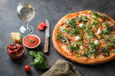 Geleneksel İtalyan pizzası, jambon, mantar, roka, mozzarella, fesleğen ve domatesli koyu arkaplan fotokopi alanı..