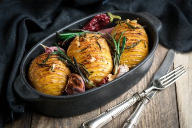 Otlu fırında patates, baharat, sarımsak ve sos kırsal bir arka planda siyah bir tavada..