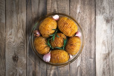 Kırsal bir zeminde yuvarlak cam bir kapta fırında patates ve sarımsak. Üst görünüm boş kopyalama alanı. 