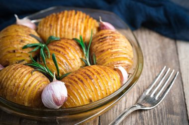 Kırsal bir zeminde yuvarlak cam bir kapta fırında patates ve sarımsak..