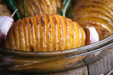 Kırsal bir zeminde yuvarlak cam bir kapta fırında patates ve sarımsak..