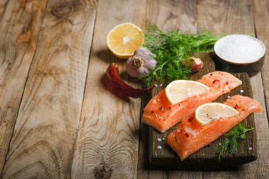 Otlu taze somon bifteği, limon, biberiye ve baharatlar kırsal bir arka plan fotokopi alanında kesim tahtasında..