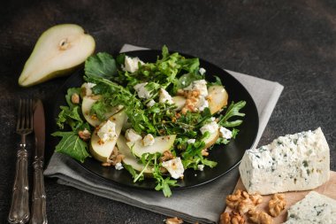 Armut salatası, mavi peynir, roka ve koyu arkaplanda baharatlı sos. Sağlıklı beslenme.