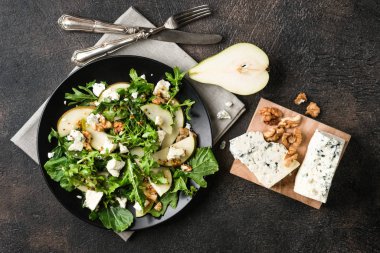 Armut salatası, mavi peynir, roka ve koyu arkaplanda baharatlı sos. Sağlıklı beslenme. Üst görünüm.