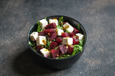 Pancar salatası, beyaz peynir, roka ve koyu arkaplanda baharatlı sos. Sağlıklı yiyecekler. Boşluğu kopyala.