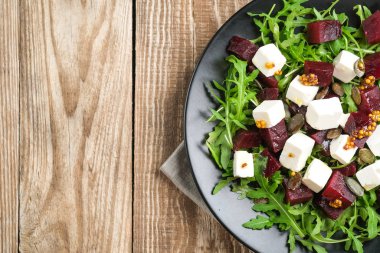 Pancar salatası, peynir, roka ve arka plan manzaralı baharatlı sos. Sağlıklı yiyecekler. Üst Manzara. Boşluğu kopyala.