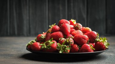 Siyah tabakta taze çilek. Karanlık bir arka planda. Boşluğu kopyala.