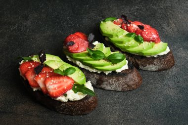 Avokado, peynir, çilek, otlar ve tohumlu bir tost veya sandviç. Bir bruschetta ya da sağlıklı bir aperatif fikri. Sağlıklı vejetaryen kahvaltısı.