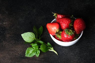 Yeşil fesleğenli seramik kasede taze çilek. Boşluğu kopyala.