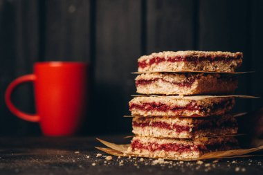 Koyu arkaplanda çay saati için ev yapımı kısa hamurlu meyveli turta ve çilekli reçel.. 