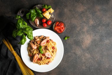 Deniz ürünleri makarnası. Karidesli bir tabak spagetti, kurutulmuş domates, fesleğen ve koyu arkaplanlı parmesan. Boşluğu kopyala.