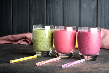 Renkli meyve suyu, ahududu, kivi, muz ve yabanmersinli taze vitaminler. Sağlıklı detoks vitamin diyeti ya da arka planda vegan gıda konsepti.