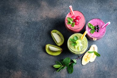 Renkli meyve suyu, ahududu, kivi, muz ve yabanmersinli taze vitaminler. Sağlıklı detoks vitamin diyeti ya da arka planda vegan gıda konsepti, fotokopi alanı olan üst görünüm.