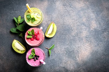 Renkli meyve suyu, ahududu, kivi, muz ve yabanmersinli taze vitaminler. Sağlıklı detoks vitamin diyeti ya da arka planda vegan gıda konsepti, fotokopi alanı olan üst görünüm.